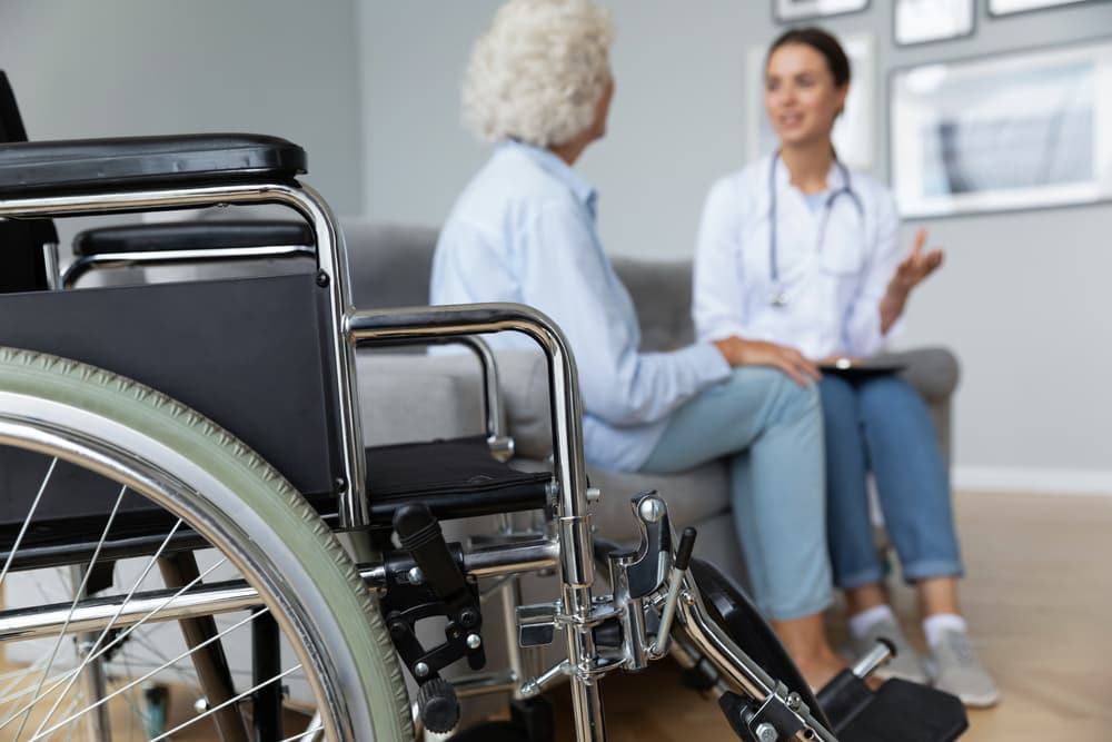 Physical therapist discussing treatment plan with an elderly woman in a wheelchair