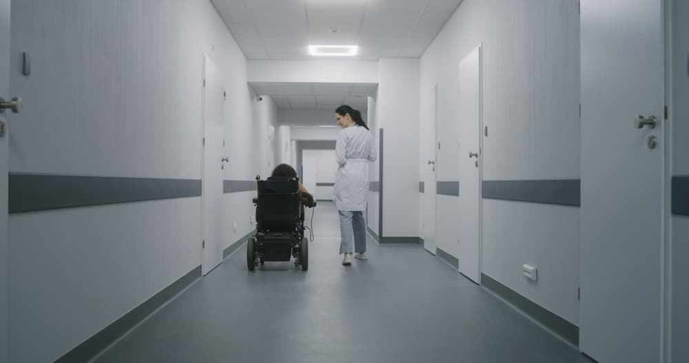 A healthcare professional discussing medical procedures with a patient in a wheel chair in a modern clinic