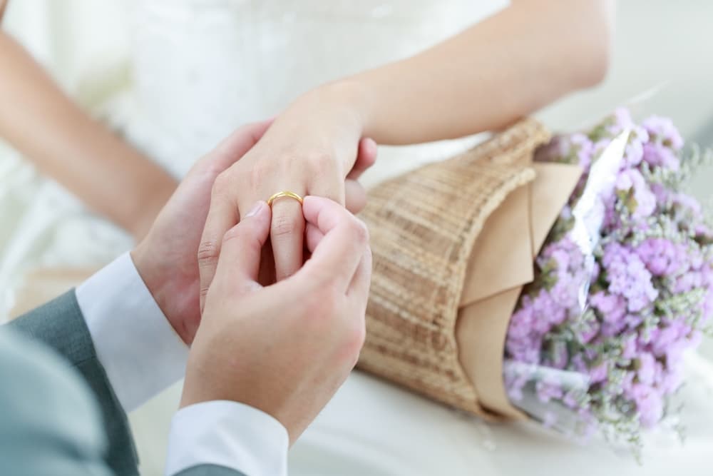Hand of The groom wears a wedding ring to the bride