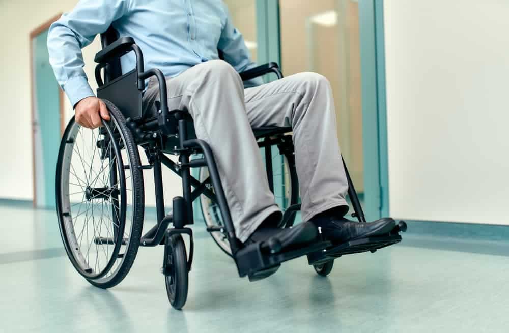 A man in a wheelchair navigates through the wide, open spaces of a modern hospital corridor