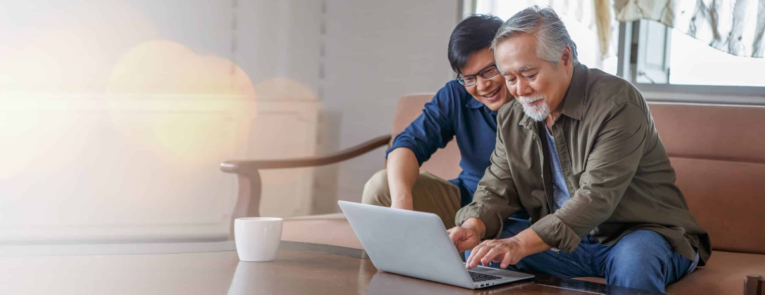 happy asian adult son and senior father sitting on sofa