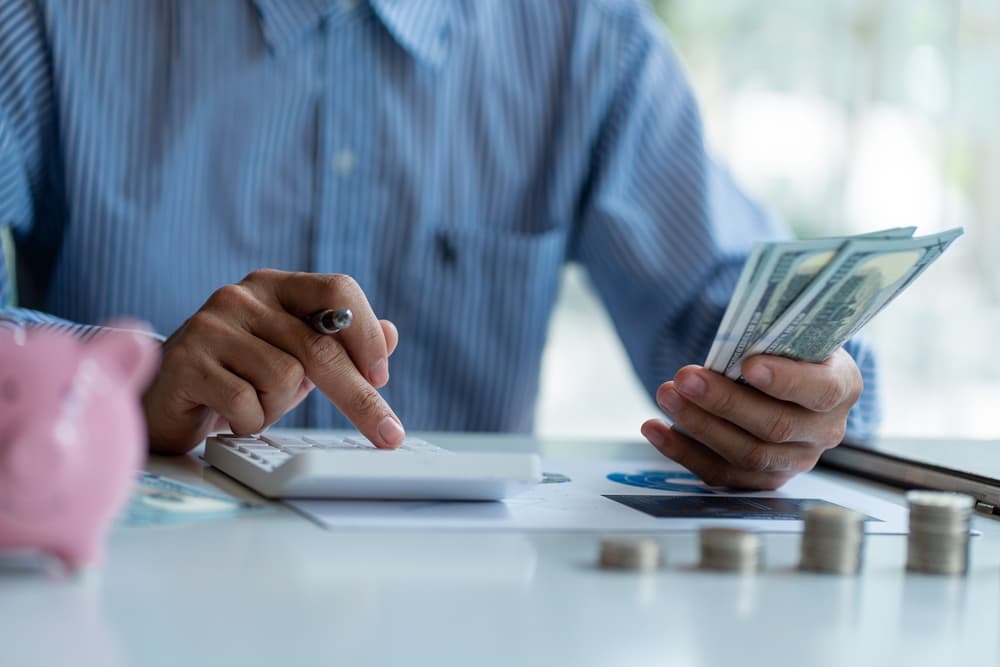 Man holding a dollar bill use money calculator Keep a record of the amount of money