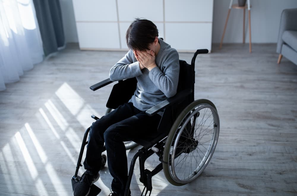 handicapped adolescent in wheelchair crying at office.